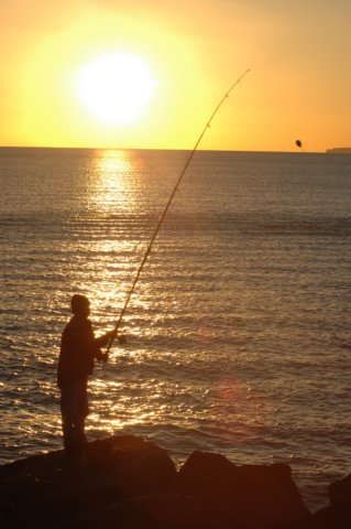 Visser bij ondergaande zon aan de Portugese kust